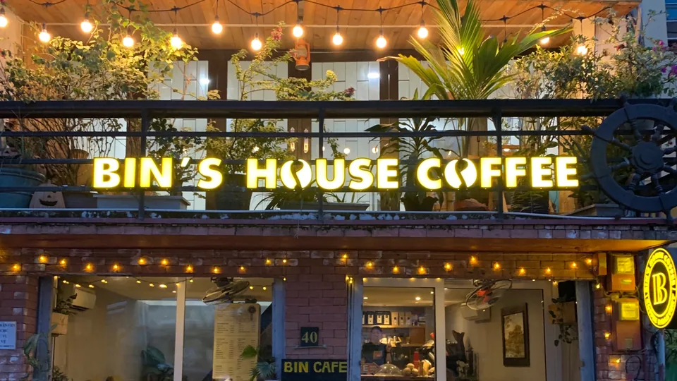 Không gian quán BIN'S HOUSE nhìn từ lối vào với bàn gỗ và đèn trang trí.